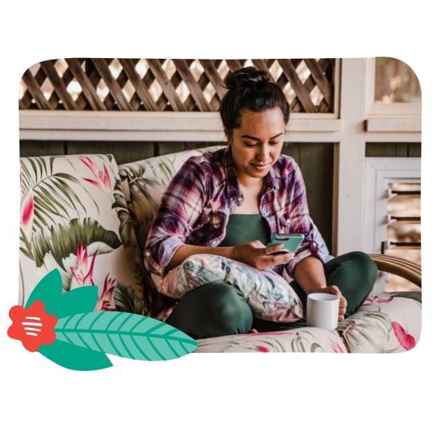 Woman sitting on bed with cup of coffee enjoying the mobile app from the comfort of her home