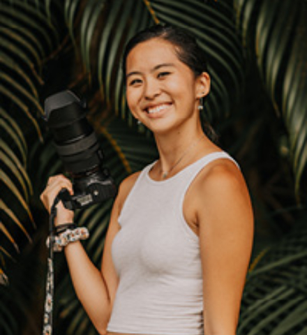 Young woman holding camera smiling outside