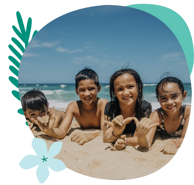 Kids laying on the sand at the beach smiling