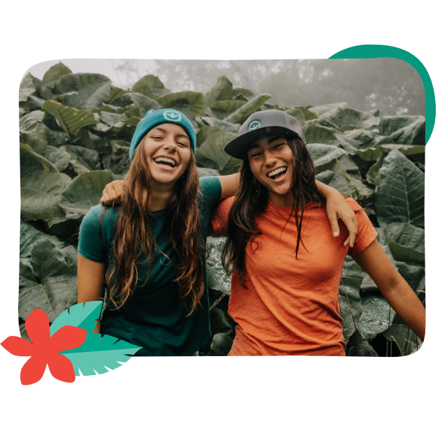 Two young women with their arms around each other laughing and smiling outside